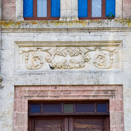 A large central gateway framed by keystones in light stone and topped by a decorated lintel. (photoIvo Piras)