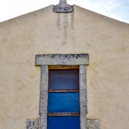 Detail of the facade with the rectangular window and the apical cross (photoIvo Piras)