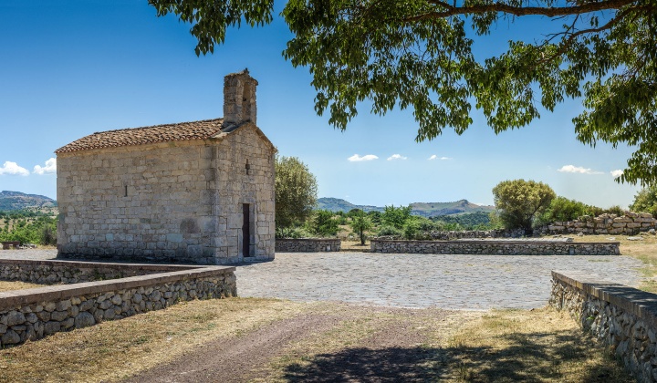 Panoramica del luogo con la chiesa e i resti di un nuraghe