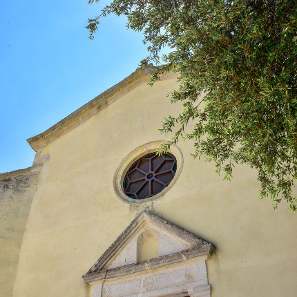 Particolare del portale timpanato in pietra e il rosone (foto Ivo Piras)